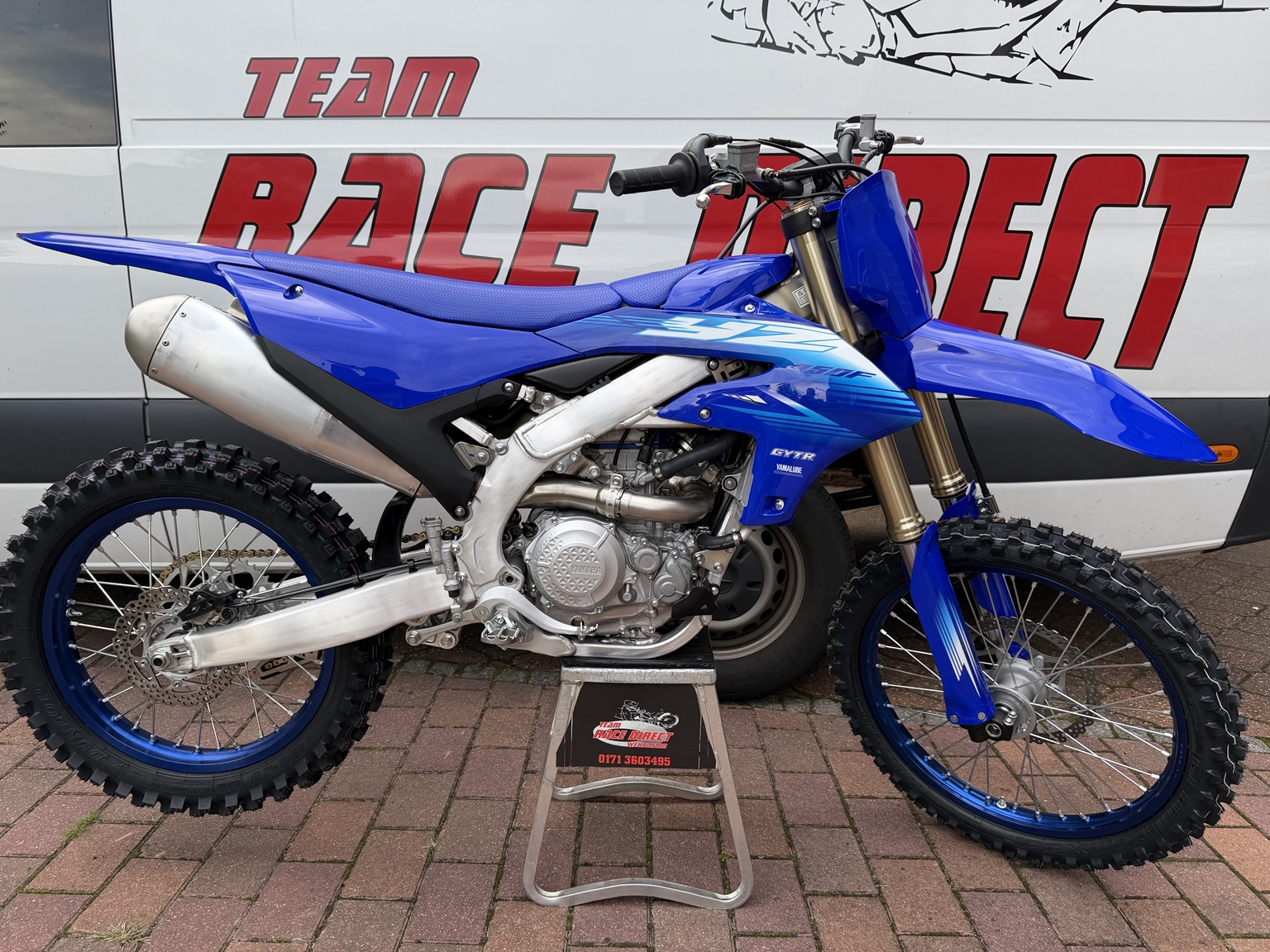 Blaues Yamaha Motocross-Motorrad vor dem Race-Direct-Fahrzeug